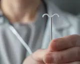 Lekarz pokazuje wkładkę domaciczną, omawiając zalecenia po jej założeniu.