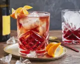 Ein erfrischender Negroni Sbagliato mit Eis und Orangenzeste, serviert auf einem goldenen Teller.