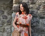 Donna con abito floreale rosa antico, cinturone marrone e borsa rotonda. I colori vivaci del vestito sono perfetti per abbinare al rosa antico.
