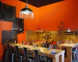 Ambiance industrielle dans un des restaurants de Chambray-lès-Tours. Tables dressées, murs orange vif, luminaires originaux.