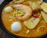 Eine Schüssel Laksa, ein beliebtes Singapur-Essen, mit Garnelen, Ei, Tofu und Nudeln in cremiger Kokosbrühe.