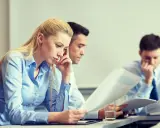 Trzy osoby pochylone nad dokumentami, analizujące dane dotyczące pracowniczego planu kapitałowego.
