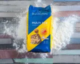 Opakowanie mąki bez glutenu "Multi Mix" rozsypane na drewnianym blacie. Idealna do wypieków dla osób na diecie bezglutenowej.