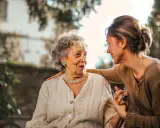 Una donna accarezza la spalla di un'anziana, un gesto di affetto che può alleviare i sintomi della demenza senile avanzata.