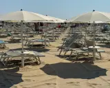 Ombrelloni e lettini pronti per il Ferragosto sulla Riviera Romagnola. La sabbia dorata attende i bagnanti.