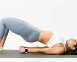 Mujer haciendo puente en colchoneta, ejercicio para fortalecer glúteos y mejorar cómo dormir para que no te duela la espalda.