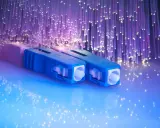 Connecteurs bleus pour télécommunication fibre optique, entourés de fils lumineux violets.