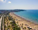 Tłum ludzi cieszy się słońcem na plaży, a w tle widać miasto. To idealne miejsce na wakacje, pełne atrakcji Costa Dorada.
