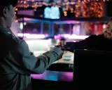 Un cliente entrega tarjetas a un camarero en un bar con luces de neón. Existe el derecho de admisión en los bares.
