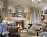 Elegancki salon z kominkiem, lustrem i meblami. Wazon z kwiatami, świece i lampy tworzą przytulną atmosferę. Co to majolika? To ozdobna ceramika, często używana do dekoracji wnętrz.