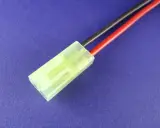 Ein gelber mini Tamiya Stecker mit roten und schwarzen Kabeln auf blauem Hintergrund.