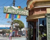 The iconic Twin Peaks sign hangs above Castro Street, a vibrant symbol of the gay area of San Francisco, adorned with rainbow flags.
