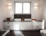 Modernes Badezimmer mit Doppelwaschbecken und einem AEG Durchlauferhitzer 24 kW an der Wand.