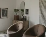 Två bruna fåtöljer framför en träbyrå med spegel och konst. En inredningsdröm inspirerad av Marie Olsson Nylander för Ellos.