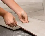Manos colocando una baldosa de porcelánico para cortar a medida.