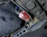 El filtro de combustible, de color rojo y transparente, está ubicado debajo del coche, cerca del tanque.
