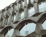 Fassade eines Gebäudes im Stil der brutalismus architektur mit geometrischen Betonformen und vielen Fenstern.