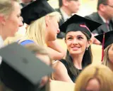 Grupa studentek w togach i biretach podczas uroczystości.
