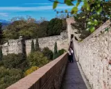 Spaziergang auf der Stadtmauer von Girona, Spanien. Zwei Frauen genießen die Aussicht auf die historische Festung und die grüne Landschaft.