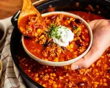 Herzhaftes Chili con Carne aus dem Dutch Oven, serviert mit einem Klecks Sour Cream und frischer Petersilie.
