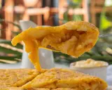 Un tenedor levanta un trozo jugoso de tortilla de espaguetis, mostrando su interior dorado y tierno.