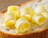 Ein Stück Brot mit aufgerollten Butterlocken. Die Butter schmilzt leicht und glänzt. Ein Genuss für den Gaumen, der an Kalium erinnert.