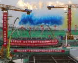 Bau von China Atomkraft-Anlagen mit Kränen und bunten Rauchsäulen. Chinesische und russische Banner feiern die Zusammenarbeit.