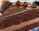 Une part généreuse de gâteau au chocolat, nappée de glaçage brillant et décorée de volutes de crème. Un délice qui rappelle l'opulence d'un opéra gateau.