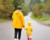 Mama i dziecko w żółtych płaszczach idą drogą. Nawet w deszczową pogodę Jastrzębia Góra oferuje atrakcje na niepogodę, jak wspólne spacery.