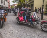 Parada motocykli i trójkołowców na brukowanej ulicy. W tle widzimy ludzi i budynki. To może być początek podróży szwecja motocyklem.