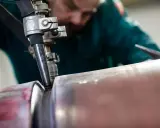 Saldatore esperto esegue saldatura ad arco sommerso su un tubo metallico, creando un giunto robusto.