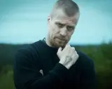 Jens Hultén, känd från filmer och tv-program, med en intensiv blick och en tatuering på handen.