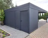 Nowoczesny garaż z wiatą, idealny na działkę bez pozwolenia. Elegancki, ciemnoszary, z praktycznymi drzwiami i zadaszeniem.