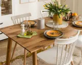 Elegancka, codzienna dekoracja stołu w salonie: drewniany blat, żółte tulipany, oliwa i przyprawy.