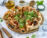 Pizza mit Prosciutto, Rucola und frisch gehobeltem Parmesan. Ein Genuss für alle Sinne!