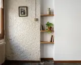 Un rincón con un radiador antiguo, un cuadro familiar y estanterías. La textura de la pared es rugosa, pero merece la pena quitar el gotelé para un acabado más liso.
