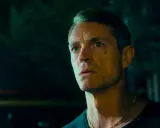 Joel Kinnaman i en mörk, intensiv scen från sin nya serie. Hans blick är fäst på något utanför bild, full av oro och beslutsamhet.