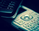 Zbliżenie na klawiatury dwóch telefonów komórkowych, jeden czarny, drugi srebrny.