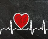 Czerwone serce na tle EKG symbolizuje zagrożenia dla zdrowia serca, w tym skutki otyłości u mężczyzn.