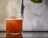 Ein erfrischender Jungle Bird Cocktail mit Eis und Schaum in einem Glas mit Rautenmuster.