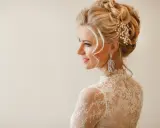 Elegancka panna młoda z perłowymi ozdobami ślubnymi do włosów i kryształowymi kolczykami.