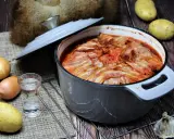 Herzhaftes russisches Essen: Ein Eintopf mit Speck überbacken, dazu Kartoffeln, Zwiebeln und Knoblauch.