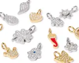 Vari ciondoli scintillanti: stella, cuore, quadrifoglio, zampa, farfalla, albero della vita, mano di Fatima, corno. Ogni gioiello ha un suo significato.