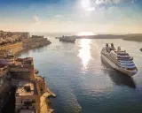MSC Crociere: documenti di viaggio pronti per una crociera al tramonto tra fortezze storiche e navi maestose.