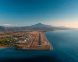 Flygplats vid havet med berg i bakgrunden. En landningsbana sträcker sig ut mot vattnet, en vy som påminner om Palermo flygplats.