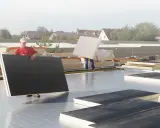 Arbeiter verlegen Dämmplatten auf einem Dach. Die Platten entsprechen der DIN 18234 und werden für die Dachisolierung verwendet.