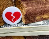 Symbol złamanego serca na stosie dolarów, między kamieniami. Nieoficjalna separacja, gdzie pieniądze dzielą.