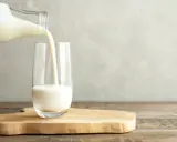 Kefir jest lekkostrawny, co widać na zdjęciu, gdy biały napój jest przelewany z butelki do szklanki.