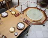Mesa elegante en el restaurante El Puente El Tejar, con vajilla dorada y una fuente ornamental en el centro.