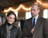 Prins William av Wales och Kate Middleton ler under en ljusslinga.